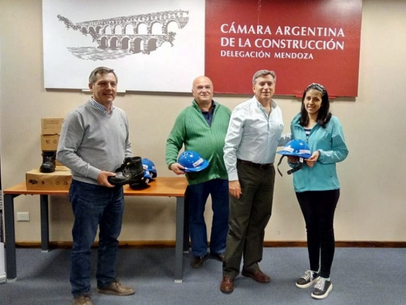 imagen El Presidente de la CAC Delegación Mendoza, Ing. Marcelo Bargazzi, junto a los ingenieros Alejandro Cantú y Martín Garbuio, entregando casco y botines de seguridad a una alumna
